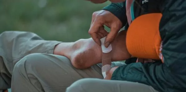 A hiking guide treats a blister on the bottom on someone's foot