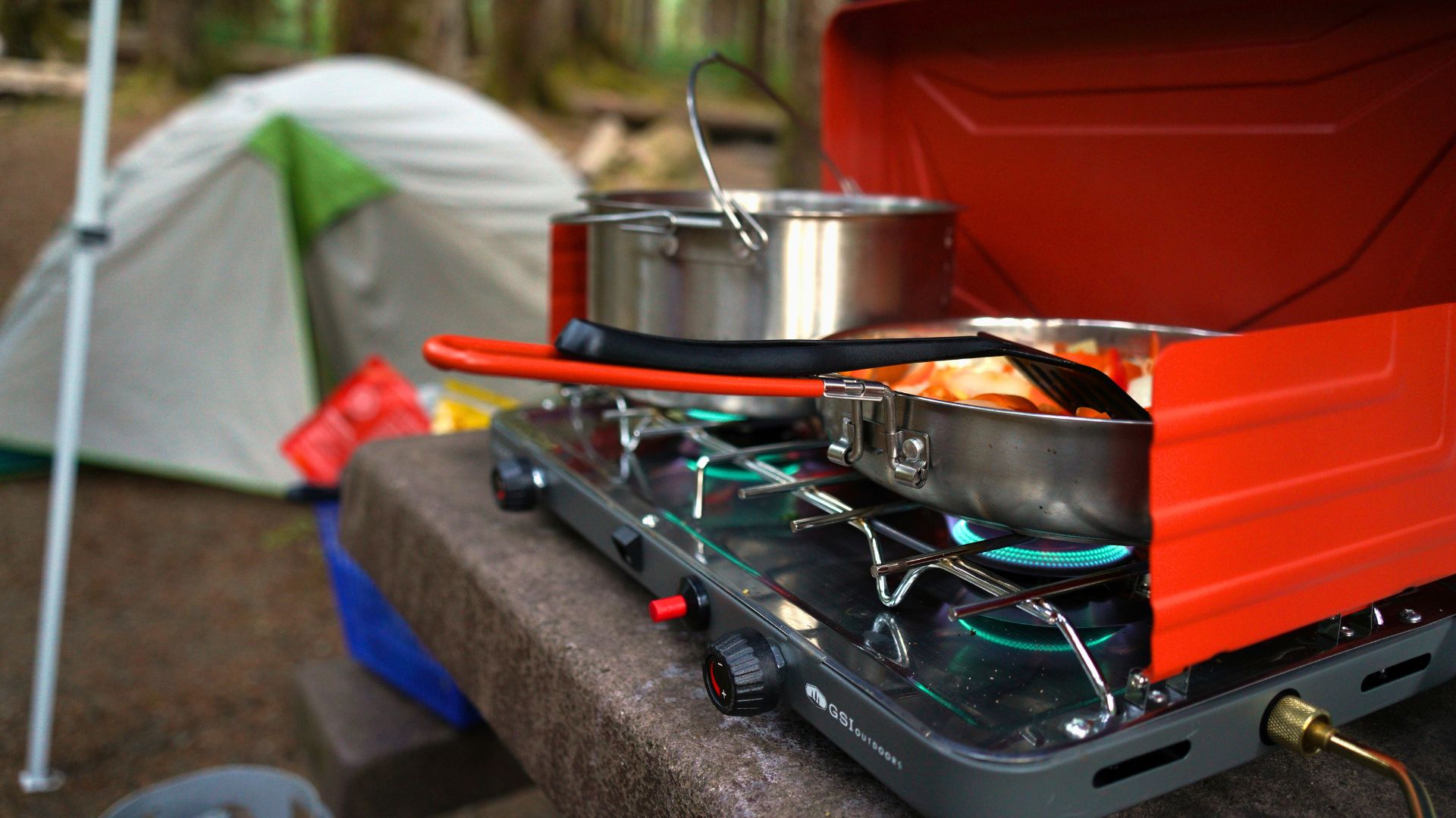 Dinner cooks on a camp stove with a tent in the background