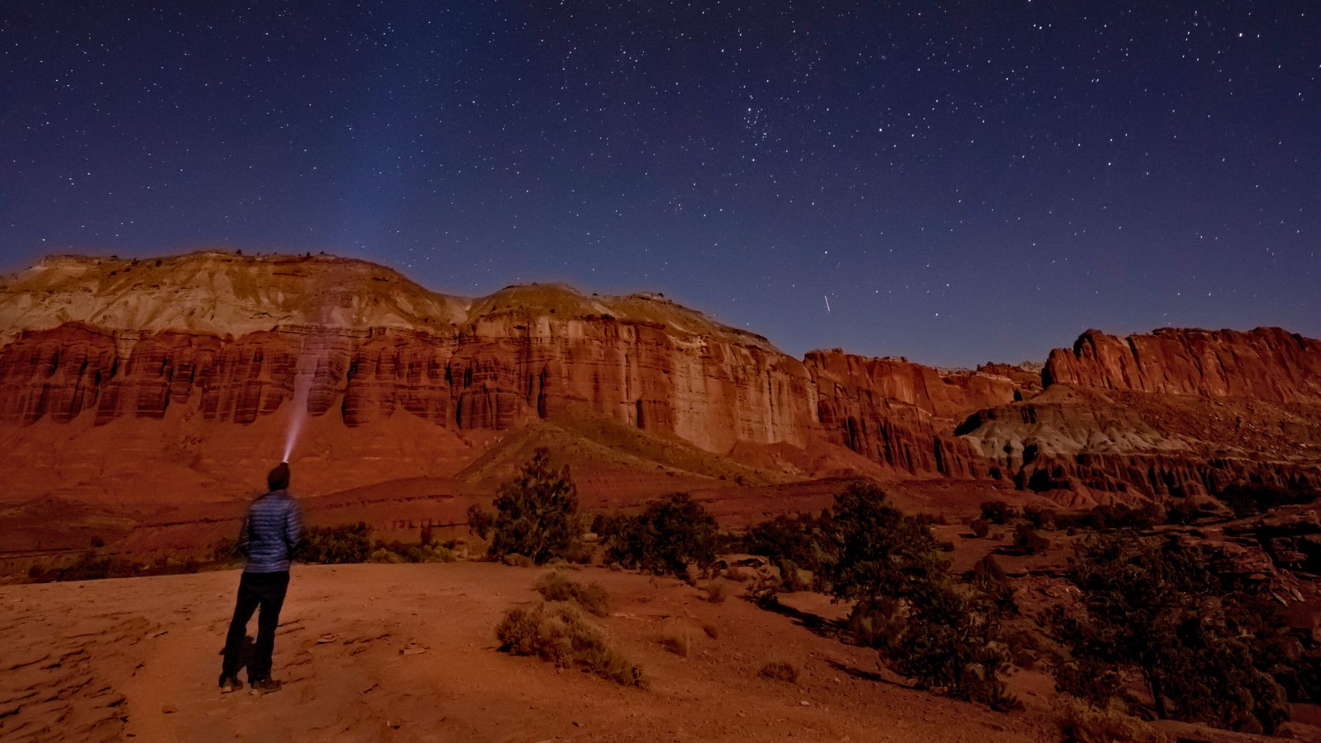 A person shines a flashlight at the night sky while stargazing in capitol reef national park
