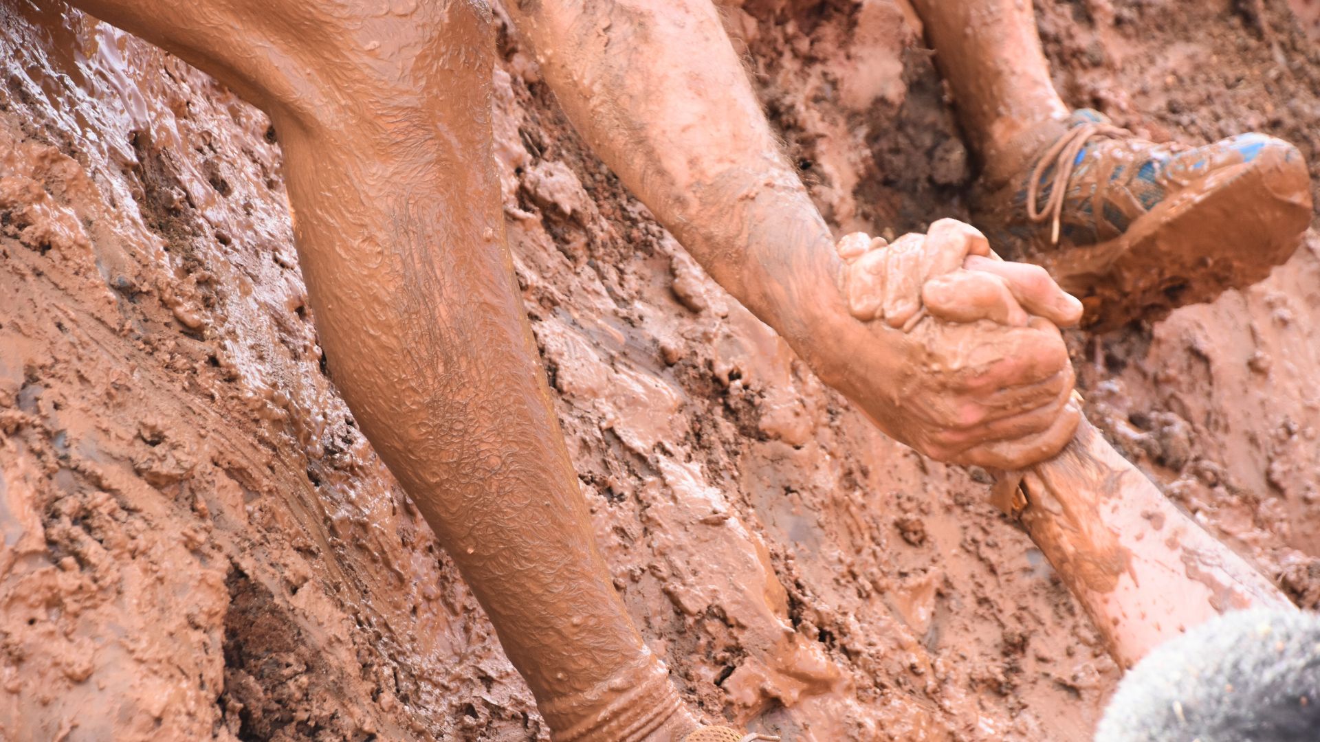 Muddy hands clasp in wet sand