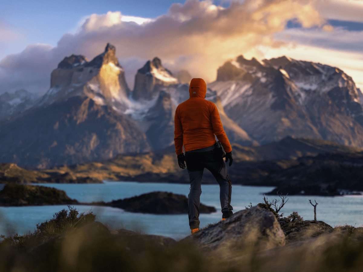 A solo hiker stands alone in front of a rugged mountain range
