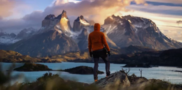 A solo hiker stands alone in front of a rugged mountain range