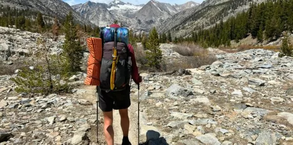 A thru hiker with a hyperlite backpack on follows a trail through the mountains