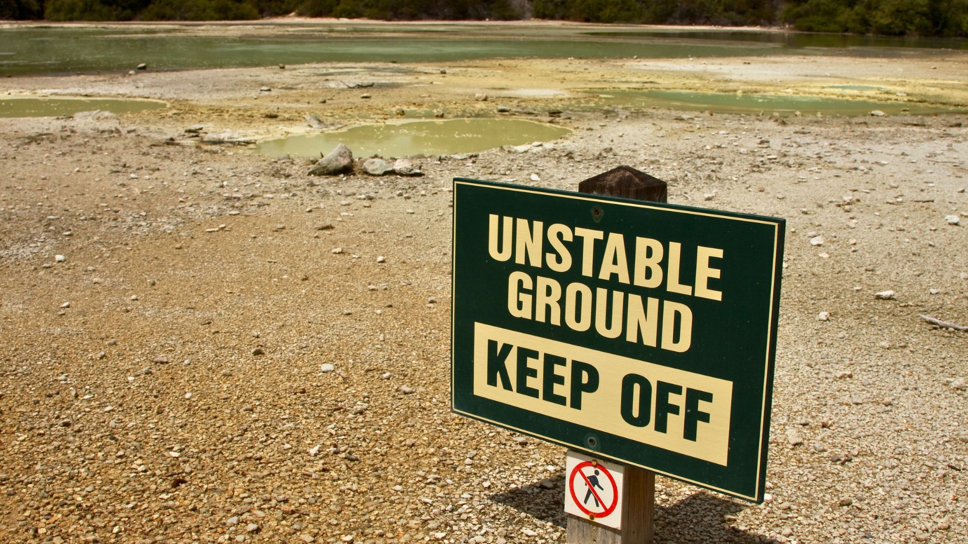 A sign in the sandy ground reads "Unstable ground, keep off"