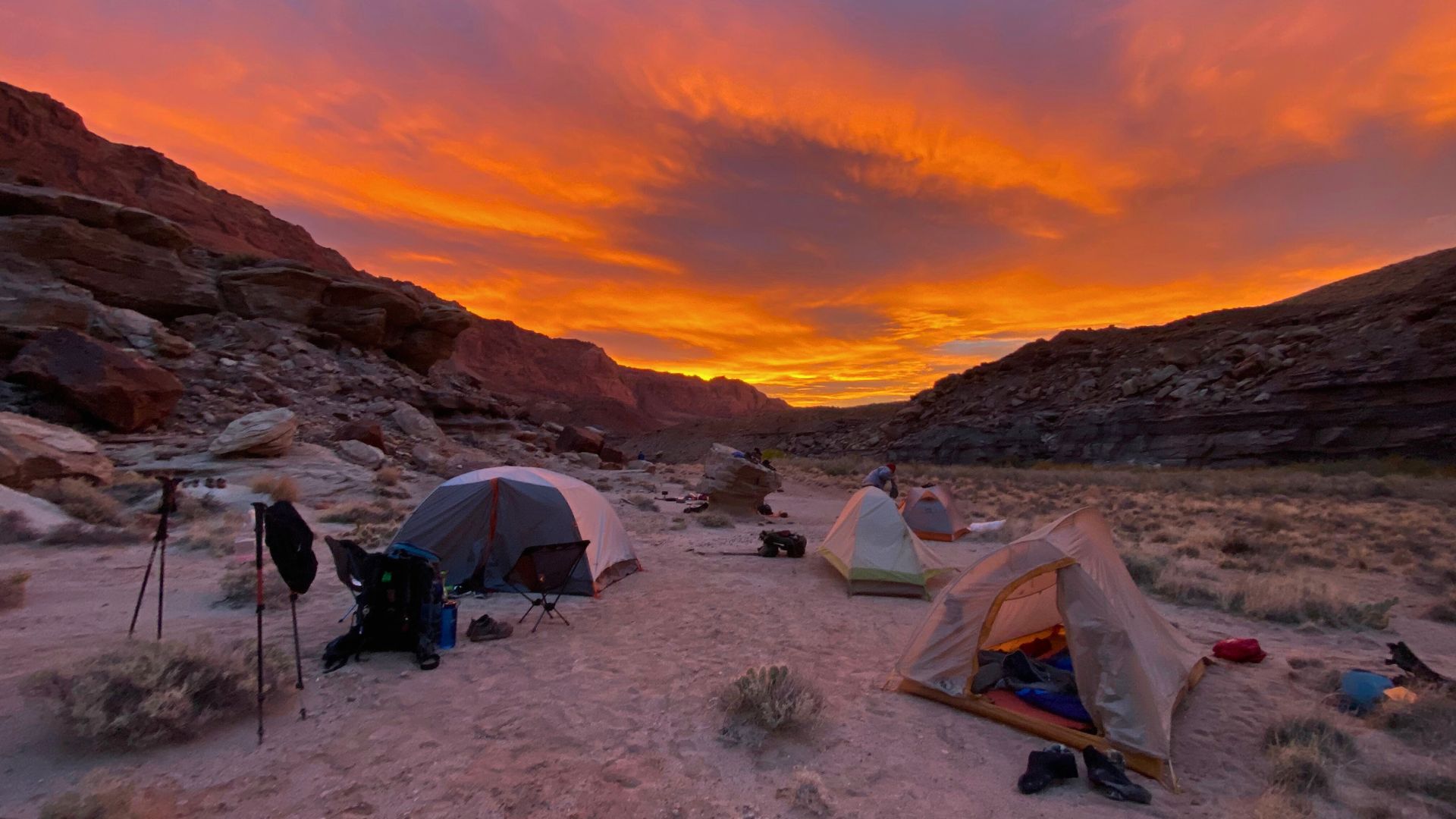Tents stand in flat sandy spot in capitol reef at sunset