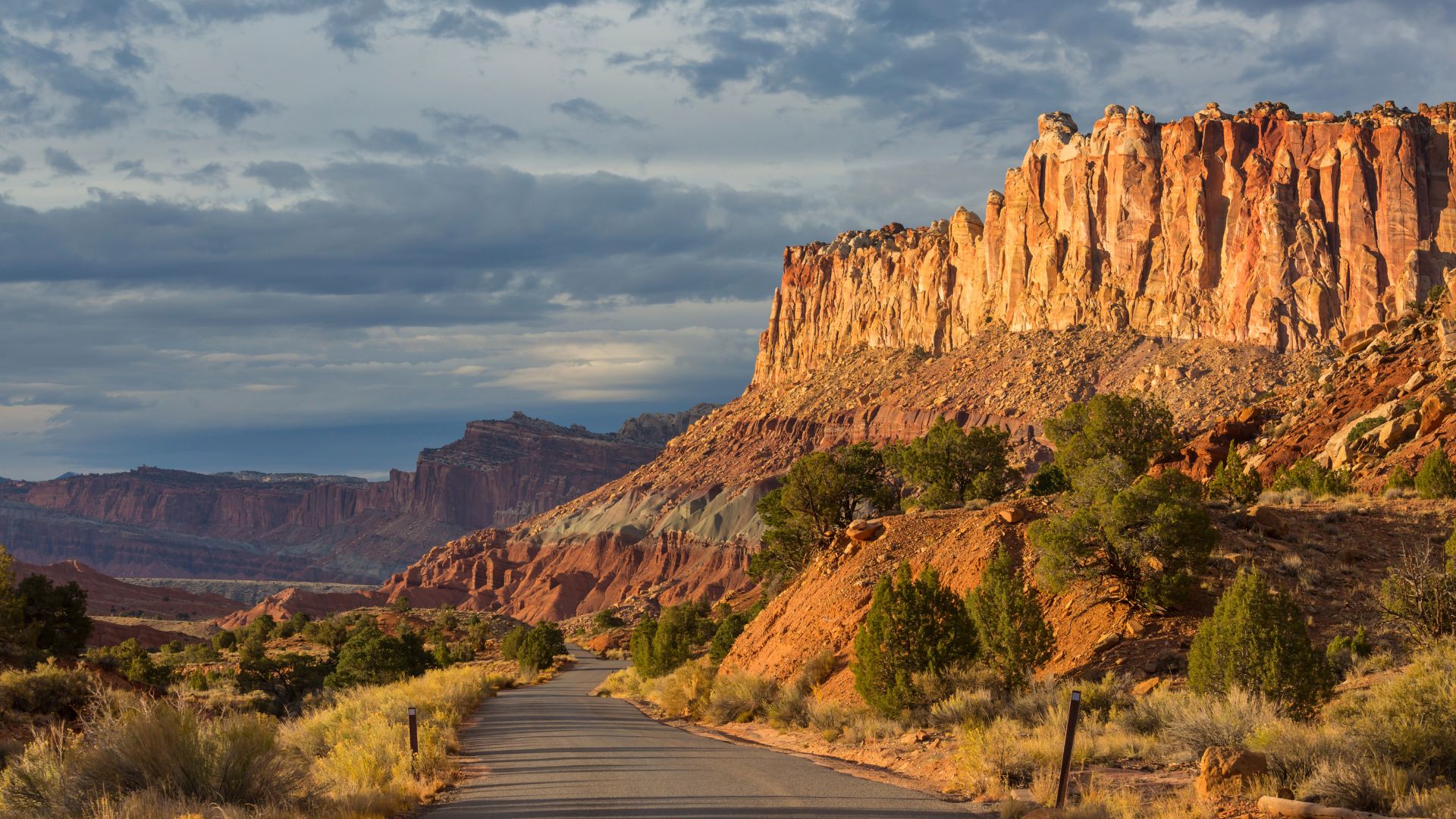 A paved road winds through capitol reef national park in golden hour