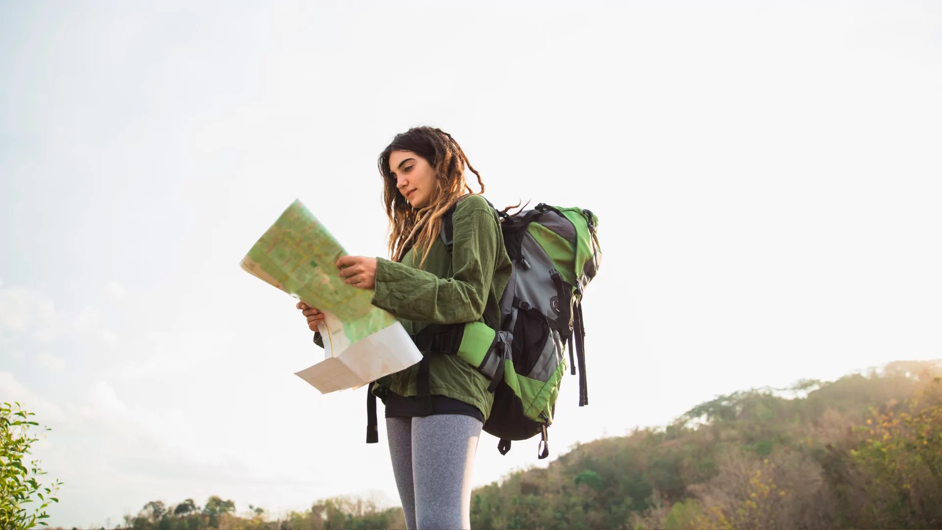 A woman with a backpack on looks at a map