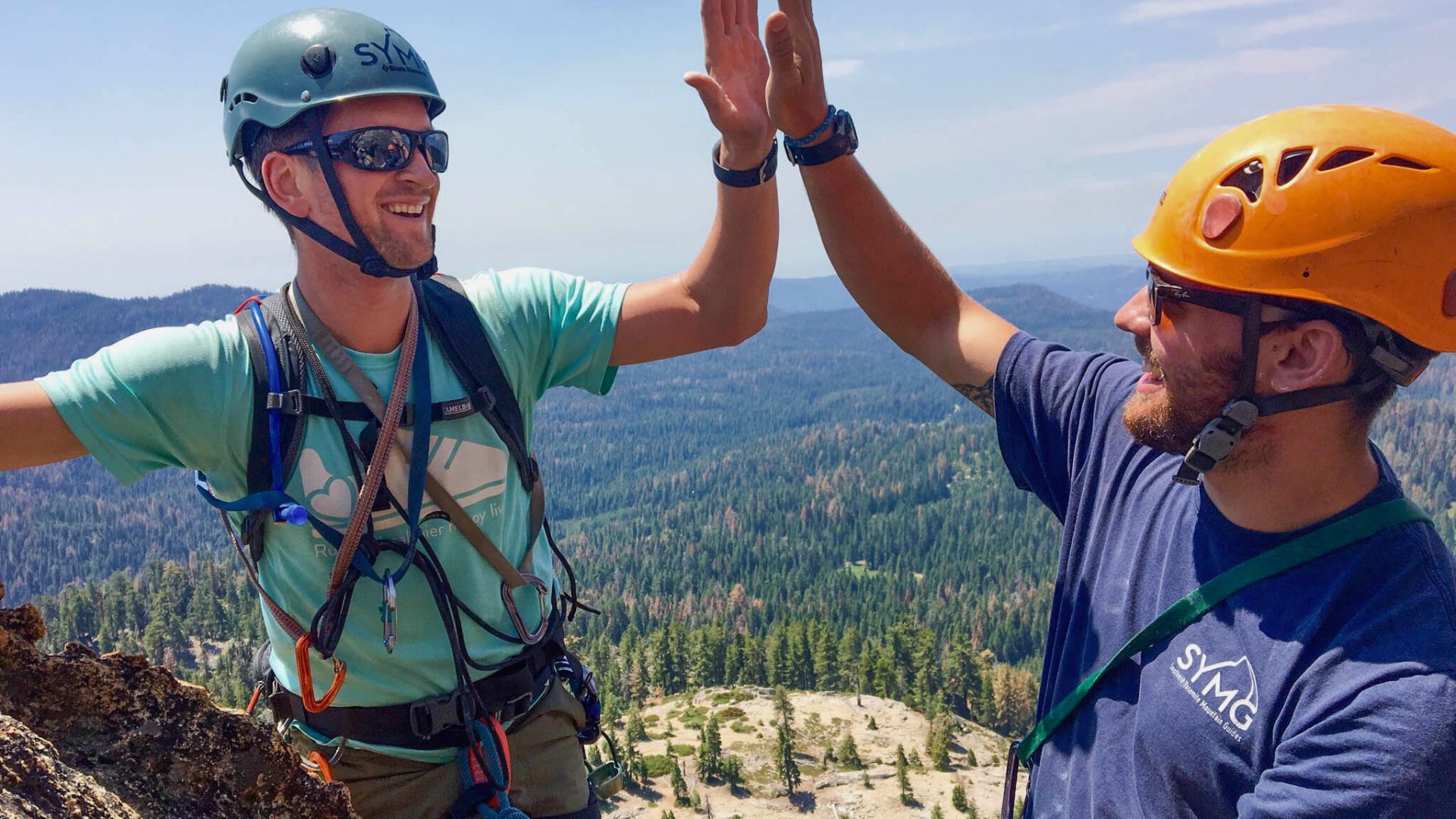 Rock climbers high five high up outside