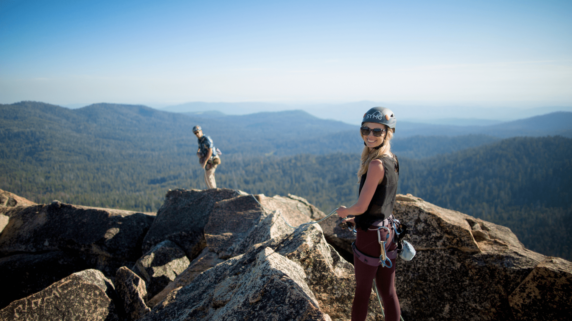 A woman looks at the camera high up on a rocky yosemite summit