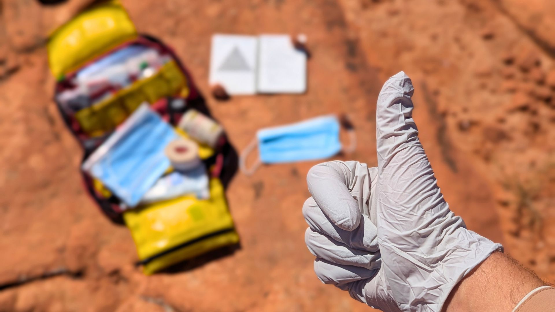 A hand wearing a medical glove gives a thumbs up