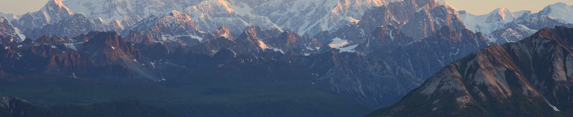 Two tents stand against a mountainous background
