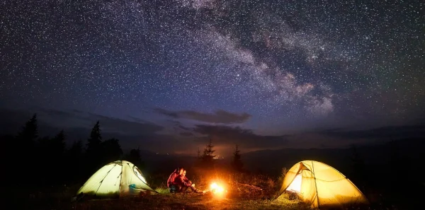 Tents at night|Meditation|Pills spill out of a bottle of melatonin|A tent in the woods under the night sky|A sleep mask|Looking out from inside a tent in a lsleeping bag|A woman does a yoga pose outdoors