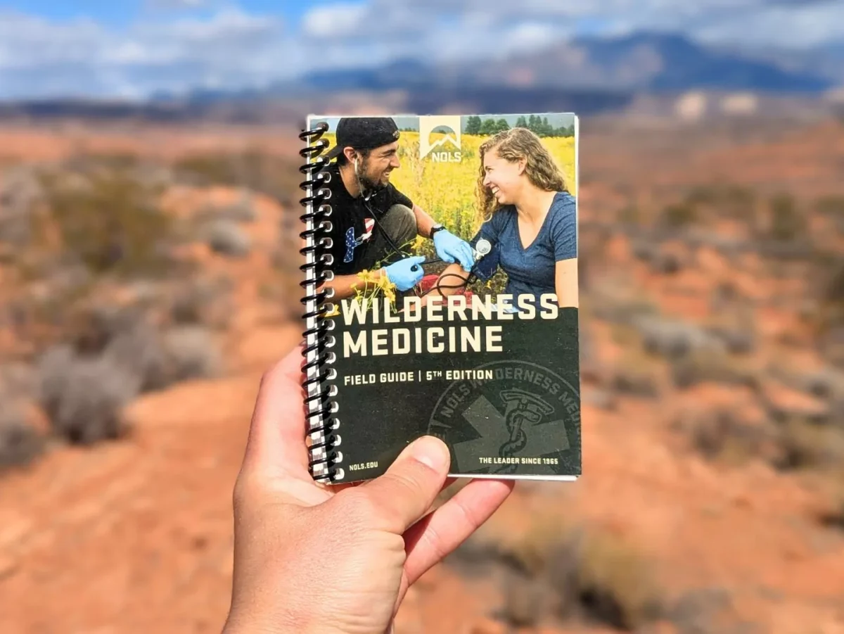 Wilderness medicine manual|An open medical text explains the steps of CPR|First aid kit