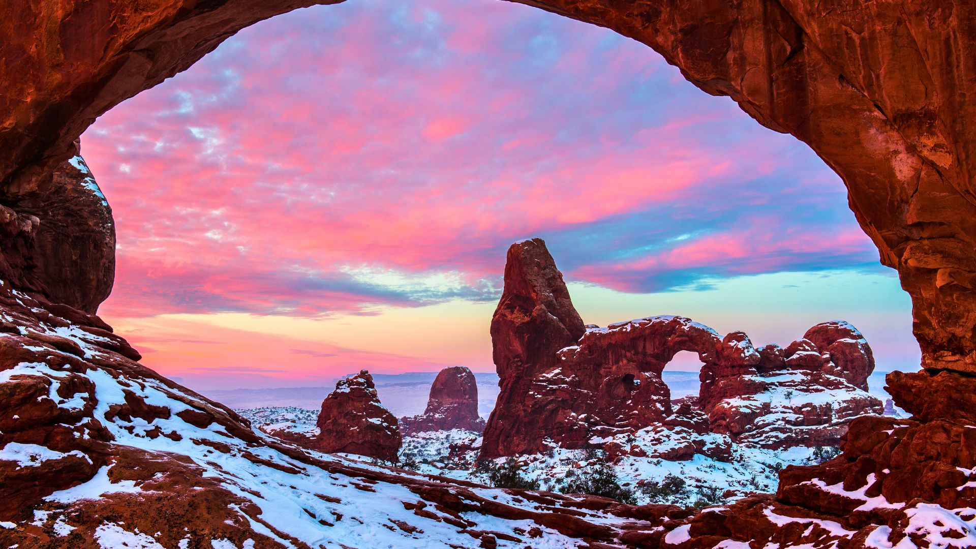 The sun rises on snow covered Arches in Moab