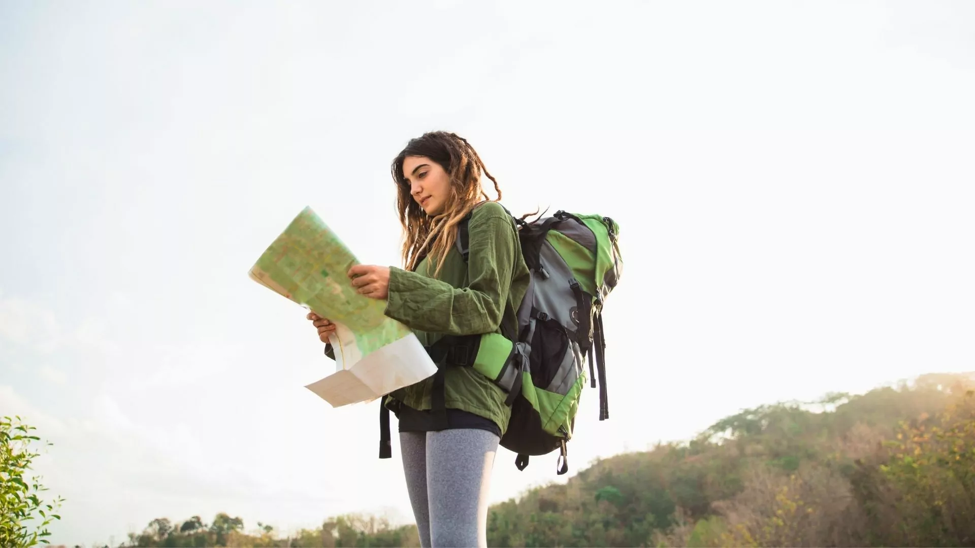 A woman with a large backpack on consults a map
