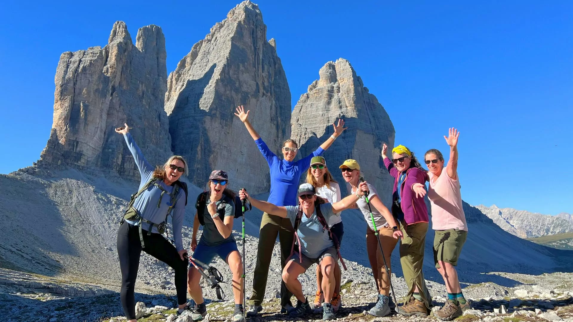 A hiking group poses enthusiastically in the Dolomites