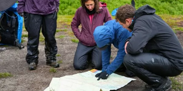 A group of people look at a map in the wilderness