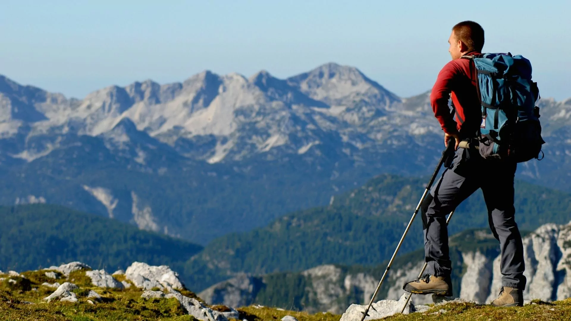 A backpacker stands looking out at the mountains