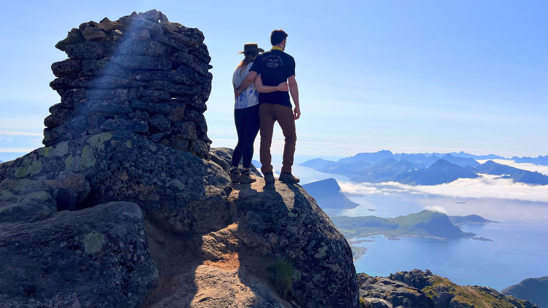Couple on mountain top looking down at the islands of Lofoten Norway