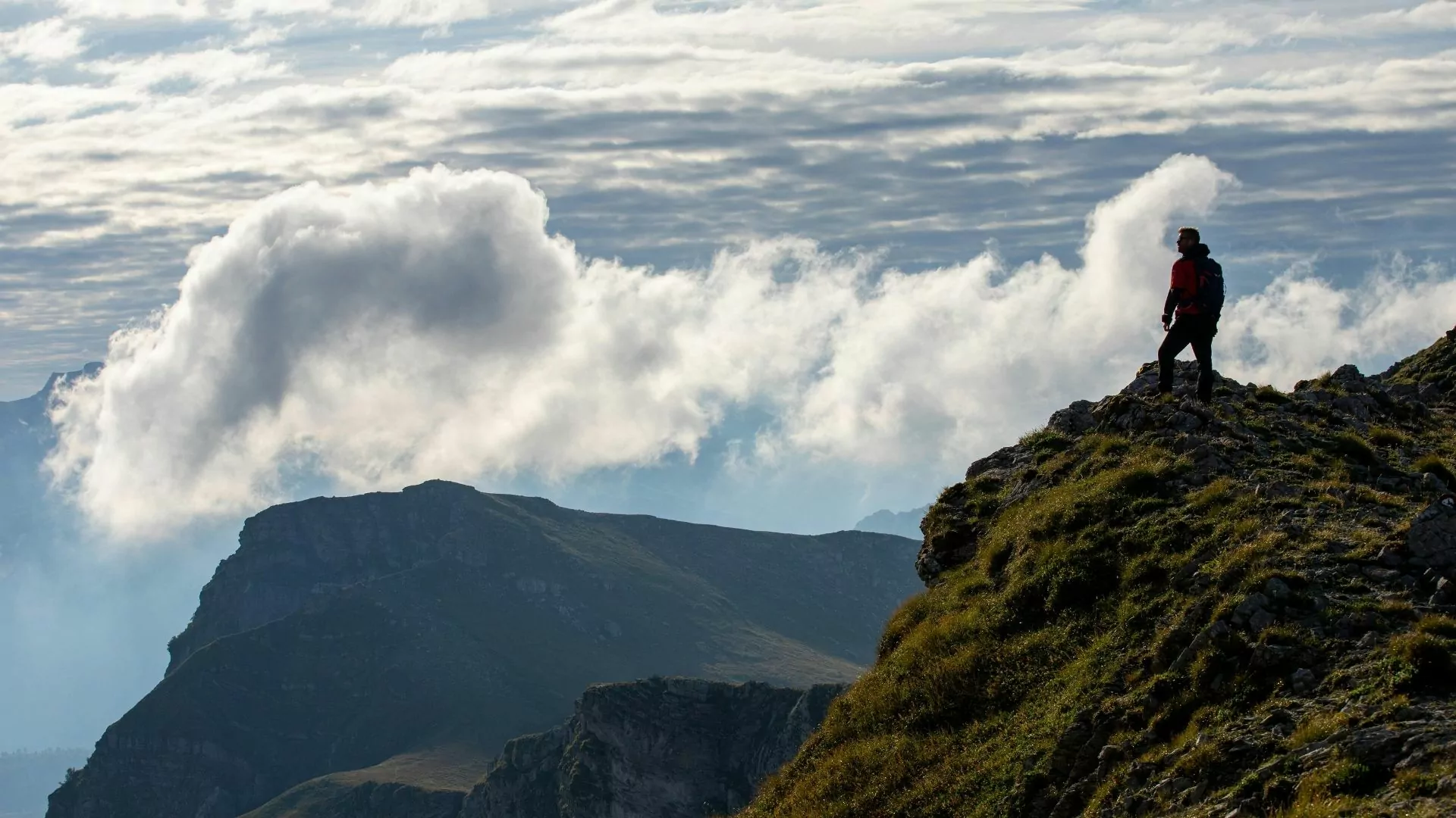 A hiker solo hiker stands on a high point looking out into the distance