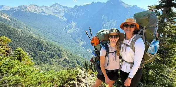 Two backpackers pose in front of Washington state summer scenery