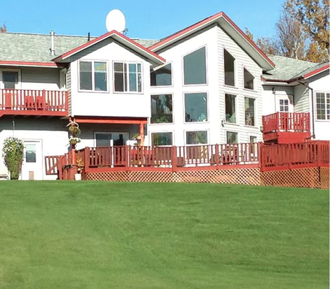 Bed and breakfast. A large home with a red deck and green lawn out front