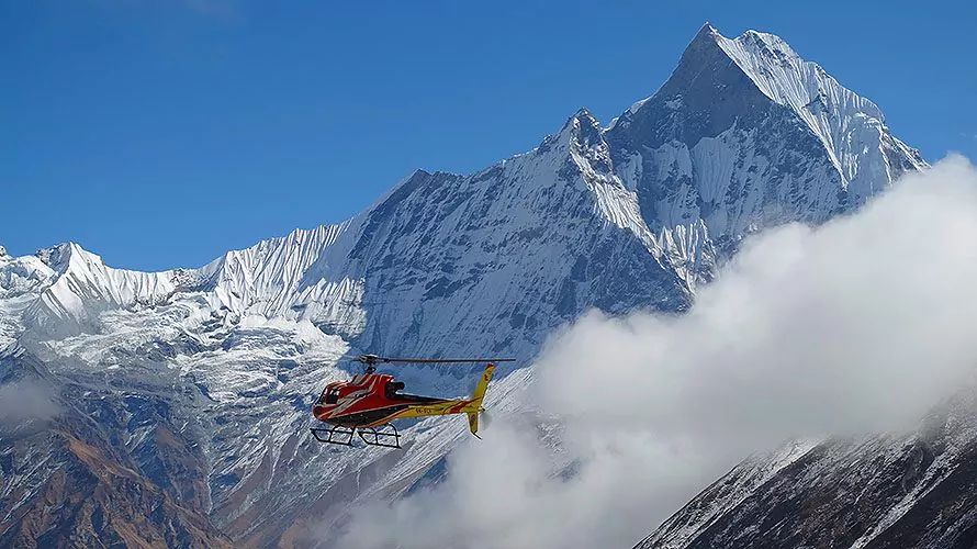 Red helicopter in front of snowy mountains