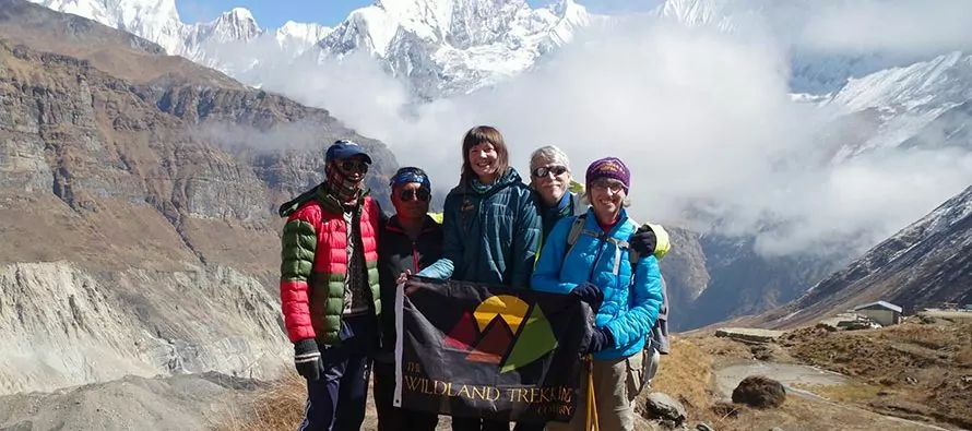 Hikers holding Wildland Trekking flag on mountain