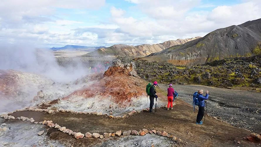 Hikers standing near Icelandic geyser