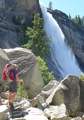 hiker standing in front of waterfall