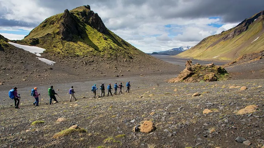 Hikers walking near stream and mountains