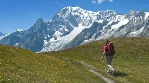 Single hiker walking on trail with mountains in background