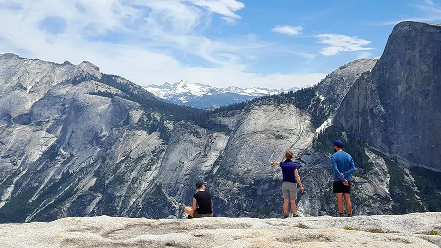 hikers standing atop stony mountain looking at view