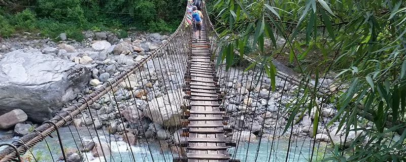 wooden suspension bridge over rocks and river