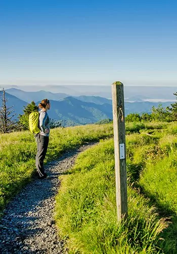 A hiker with a backpack looks out over the Blue Ridge mountains