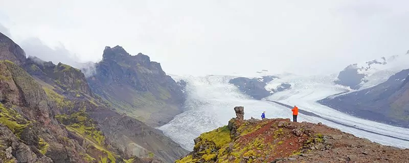 Hikers on grassy cliffs overlooking water