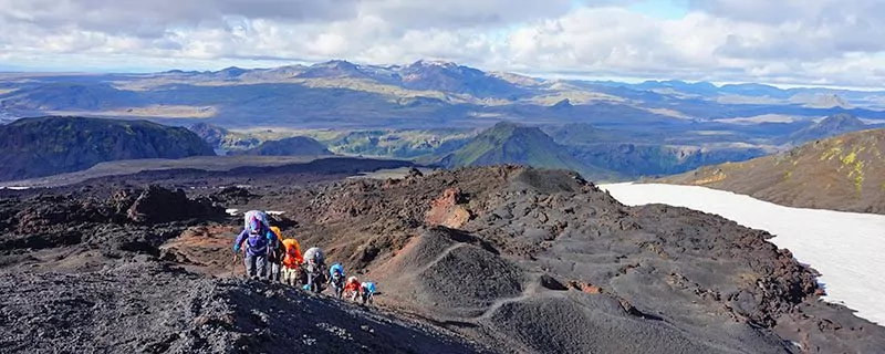 Hikers climbing rocky hill in Iceland