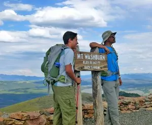 Hikers pose with a summit trail sign in Yellowstone National Park