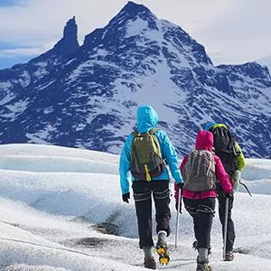 Three hikers walking toward snowy Patagonian mountain