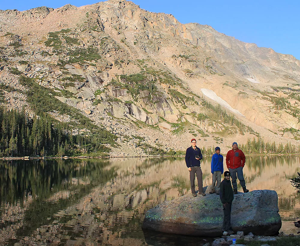 Hikers pose on a boulder in a lake in Rocky Mountain National Park