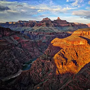 sunset hues drape over the Grand Canyon with blue skies and red rock formations