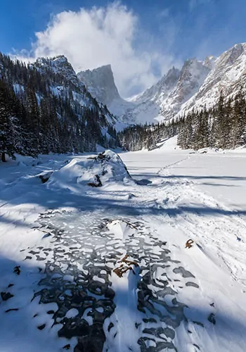 Snowy trails lead into the depths of the misty mountains of Rocky Mountain National Park