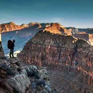 A silhouetted hiker looks out across the Grand Canyon