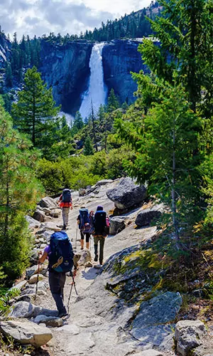 Hikers approach a massive waterfall in Yosemite National Park