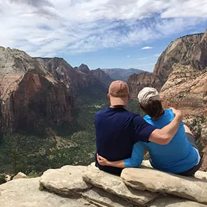 Two hikers embrace atop the summit in Zion National Park