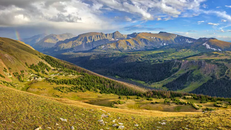 Panorama of Rocky Mountain at sunset, with rainbow.