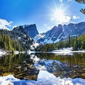 Sunlight shines across a snowy alpine lake in Rocky Mountain National Park