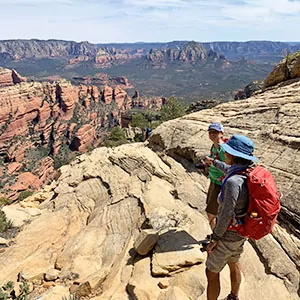 Two hikers enjoy the view from atop rock formations in Sedona