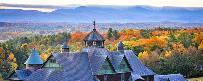 A barn and autumn leaves with misty mountains in Vermont