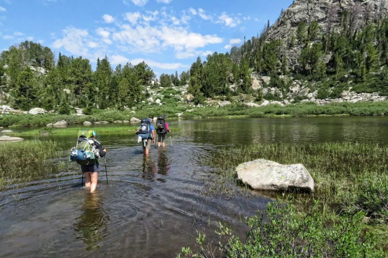 Hikers crossing knee-high water in the wind river range;